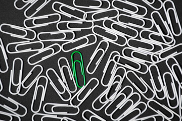 Green paper clip inovative idea concept on black background. stand out of the crowd
