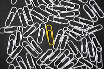 Yellow paper clip inovative idea concept on black background. stand out of the crowd