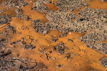 Background of brown mud with bright orange chemicals, environmental pollution, toxic waste hazard, horizontal aspect