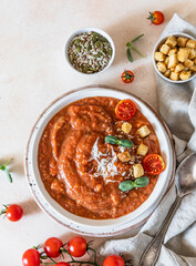 Vegetable soup with baked tomato, bell pepper, cream, breadcrumbs and micro greens in white bowl on light concrete background. Top view.