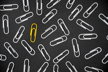 Yellow paper clip inovative idea concept on black background. stand out of the crowd