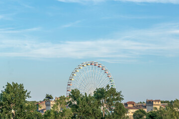 Ferris wheel in the amusement park as tourist attraction on the background of blue sky with copy space
