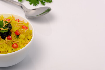 Indian breakfast Poha garnished with pomegranate seeds, chopped green chilly, coriander leaves and curry leaves.