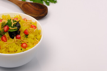 Indian breakfast Poha garnished with pomegranate seeds, chopped green chilly, coriander leaves and curry leaves.
