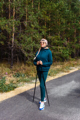 smiling woman with a long braided braid stands in the park. Nordic walking