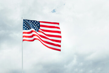 USA America flag waving in the wind over cloudy sky.