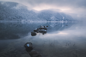 Beautiful mountain and lake winter landscape of calm reflection on Kootenay Lake with sunrise or...