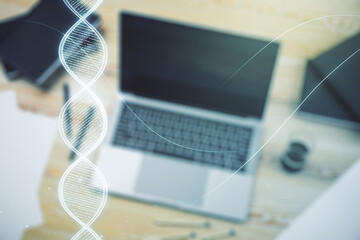 Double exposure of creative DNA hologram on laptop background. Bio Engineering and DNA Research concept