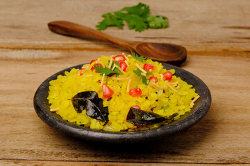 Indian breakfast Poha garnished with pomegranate seeds, chopped green chilly, coriander leaves and curry leaves.