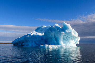 Beautiful iceberg in Arctic sea at sunny day. Big piece of ice in sea close up.