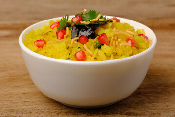 Indian breakfast Poha garnished with pomegranate seeds, chopped green chilly, coriander leaves and curry leaves.