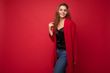 Portrait of positive cheerful fashionable woman in formalwear looking at camera isolated on red background with copy space