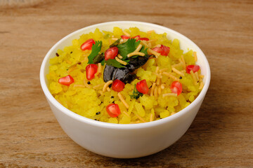 Indian breakfast Poha garnished with pomegranate seeds, chopped green chilly, coriander leaves and curry leaves.