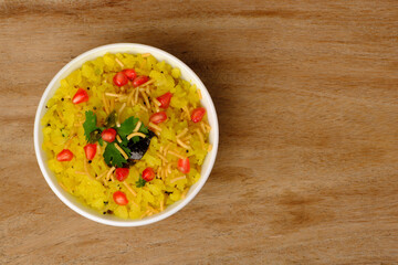 Indian breakfast Poha garnished with pomegranate seeds, chopped green chilly, coriander leaves and curry leaves.