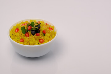 Indian breakfast Poha garnished with pomegranate seeds, chopped green chilly, coriander leaves and curry leaves.