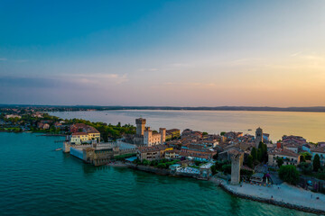 Naklejka premium Aerial panoramic view of Sirmione city old town on lake Garda in Lombardy, Italy. Evening photo with a castle in a center
