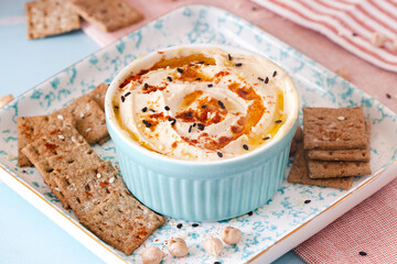 hummus with paprika and sesame seeds in a blue bowl