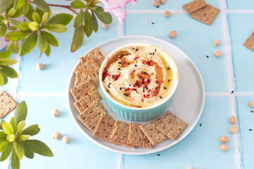 hummus with paprika and sesame seeds in a blue bowl