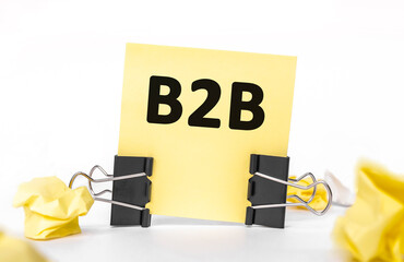 Text B2B on a yellow piece of paper for notes. Stationery Paper clips, crumpled paper. financial business concept. sale, discounts. Business to business