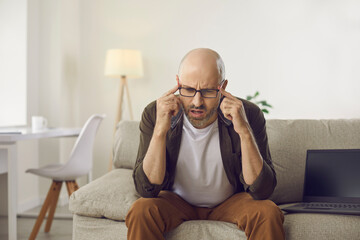 Man begins to realise something. Serious confused thinker sitting on sofa with laptop computer at home thinking, trying to understand situation, find answer to question, guess, resolve complex problem