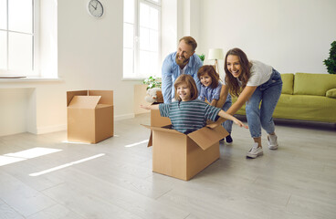 Fototapeta na wymiar Happy excited family having fun in new home. Joyful first-time buyers with children fooling around with boxes in spacious living room interior. Real estate, residential mortgage, buying house concept