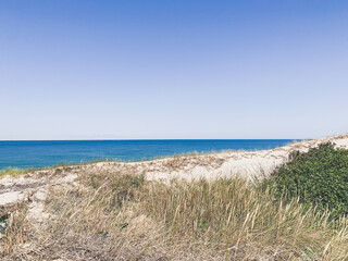 Fototapeta na wymiar White sand dunes with some grass and seascape background