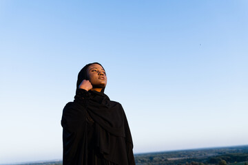 Black muslim woman weared in black robe on blue background. Islamic religion. Celebrating ramadan