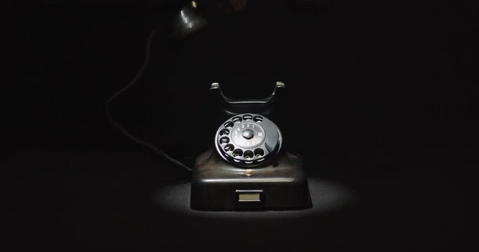 Hand picking up and hanging vintage black phone