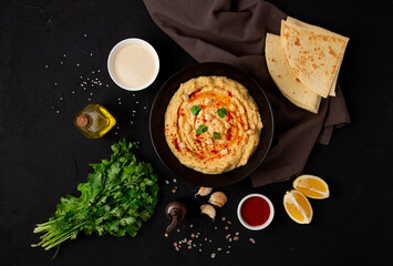 Classic chickpea hummus with tahini, olive oil, garlic and paprika, homemade, on a black background, top view, no people,