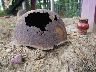 Authentic Second World War helmet with bullet hole. Rusty helmet on the grave - memorial in Orzega,...