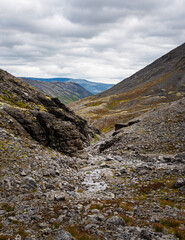 landscape of the Khibiny mountains with rocks and a mountain stream on a cloudy day. Kola Peninsula, Russia