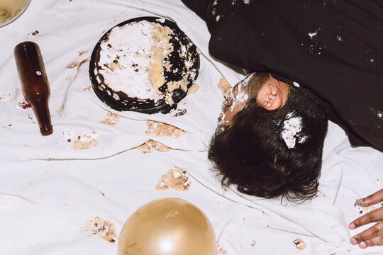 Drunk man lying on messy cloth with smashed cake