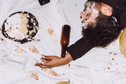 Drunk man lying on messy cloth with smashed cake