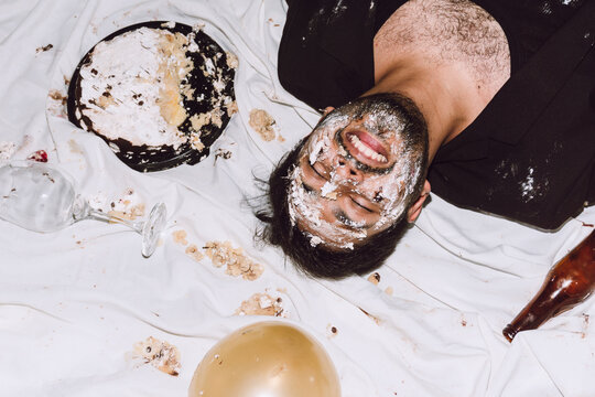 Happy man in smashed cake with eyes closed