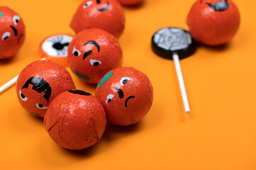 Halloween candy with black spiders,angry pumpkins and cobweb on orange color background,top view