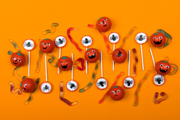Halloween candy with black spiders,cobweb,smiling pumpkins and  jelly worms on orange color...