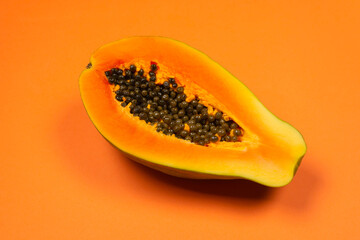 Papaya fruit on a orange background. Half papaya.
