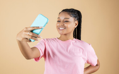 pretty young african woman making selfie with her smartphone beige background