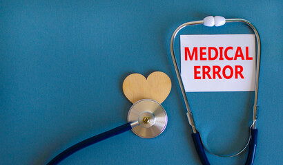 Medical error symbol. White card with words Medical error, beautiful blue background, wooden heart...