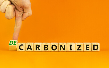 Carbonized or decarbonized symbol. Businessman turns a wooden cube and changes words 'carbonized' to 'decarbonized'. Orange background, copy space. Business, Carbonized or decarbonized concept.