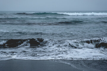 Panoramic view of the pacific ocean with waves, the horizon with cloudy sky and the shore and beach