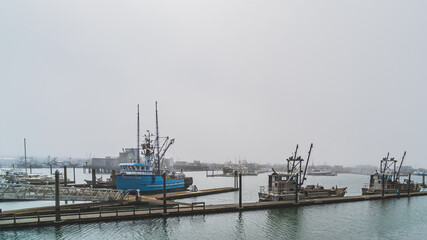 Fishing trawlers at dock in foggy weather in a marina