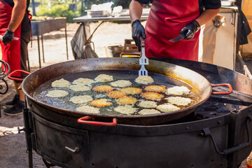 Chef fries potato pancakes in a large frying pan