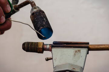 Trabajador con soplete de gas para soldar tubería de cobre con estaño
