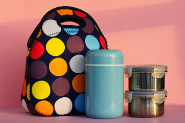 snack on a break with a lunchbox. colorful handbag, blue thermos and two metal containers with food. lunch for a schoolboy or an office worker.