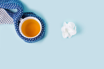 Cup of chamomile tea and crumpled paper wipes on blue background. Seasonal diseases and treatment of colds, flu, heat. Prevention of virus. Copy space for