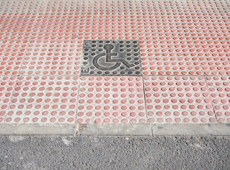 Adaptation of a sidewalk for the disabled people in front of a zebra crossing, with a handicapped accessible sign in the center, copy space all around
