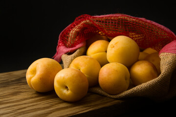 Image of a bag of apricots on wood and dark background with copy space