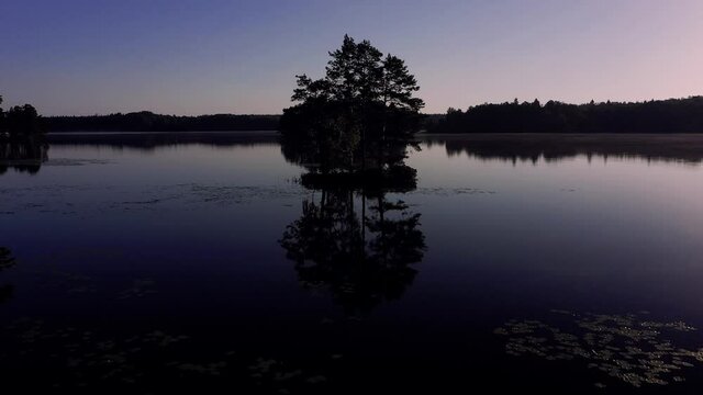 Kleine Insel im See. Schwedischer See im Smaland vor sonnenaufgang zur blauen Stunde. Kleine Insel mit Fichten spiegeln sich im See. Nebel und Spiegel.