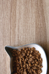 Cat shaped bowl filled with dry cat food. Top view.